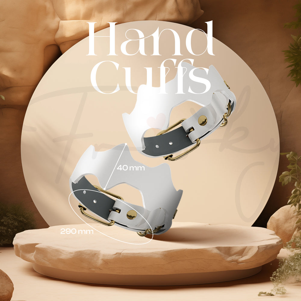 Pair of white and gold hand cuffs displayed upright on a wooden platform