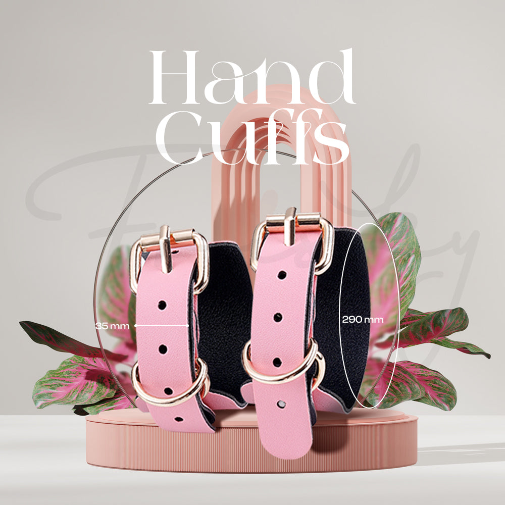 Pair of pink and black padded hand cuffs presented upright with tropical plant accents