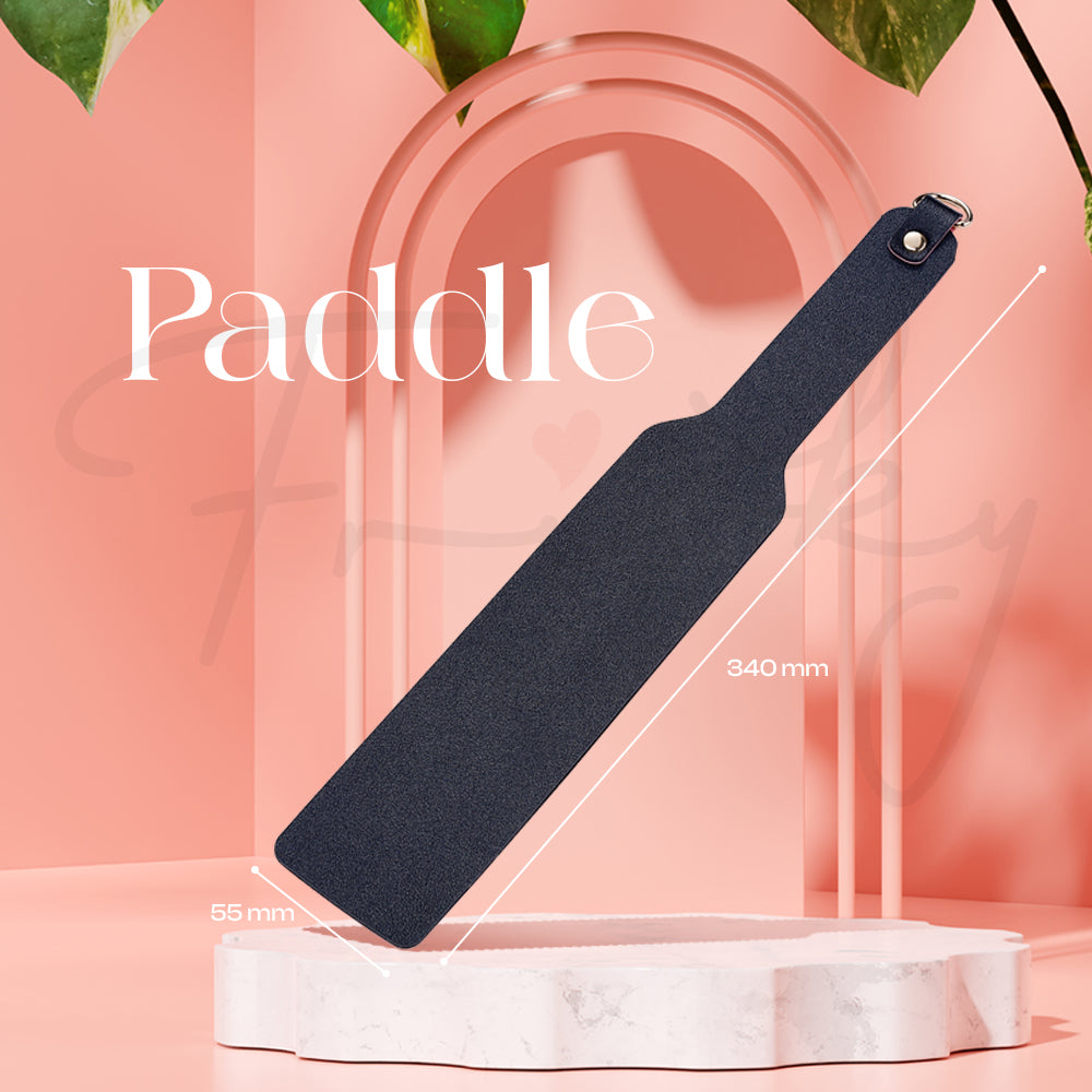 Black paddle displayed standing on a clear base against a light pink background.