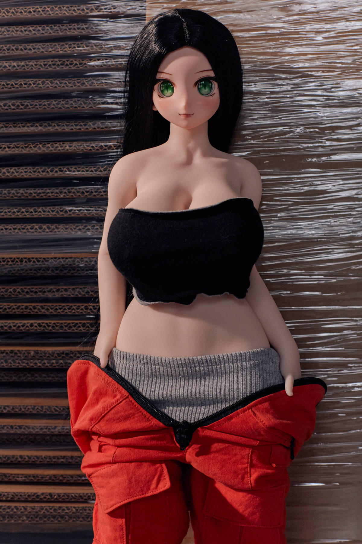 CLIMAX DOLL Mini J60cm P Hybrid - Rina (Cinnamon) close-up with the red jumpsuit pulled down to her waist, black bandeau top, black waistband visible, warehouse backdrop