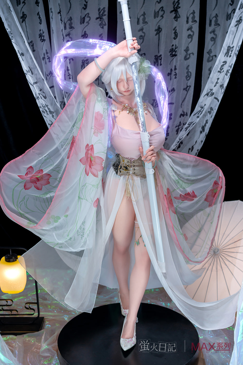 Full-body view of the Firefly Diary Doll 160 cm Max Series Silicone - Liu Li V3 in a fantasy setting. The doll features short white hair with green floral accessories and wears a flowing, translucent white and pink floral robe over a pink slip. She is standing on a dark circular platform, holding a long white staff, surrounded by traditional calligraphy scrolls and a lit paper lantern.
