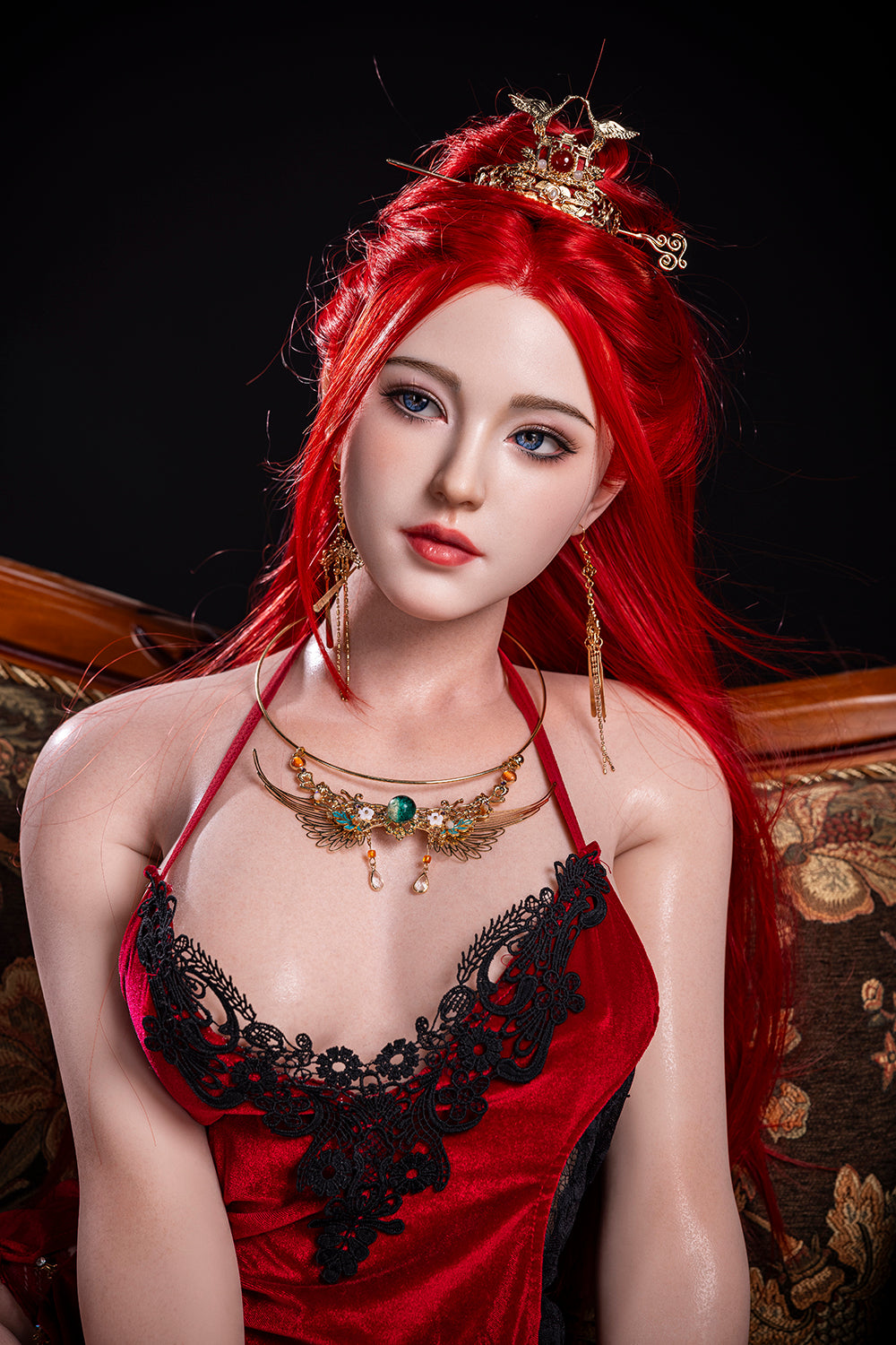 Portrait of the Starpery Dache Zheng doll, a 169 cm silicone figure with long, vibrant red hair and blue eyes, wearing an ornate gold hairpiece and a red velvet lingerie top with black lace trim.