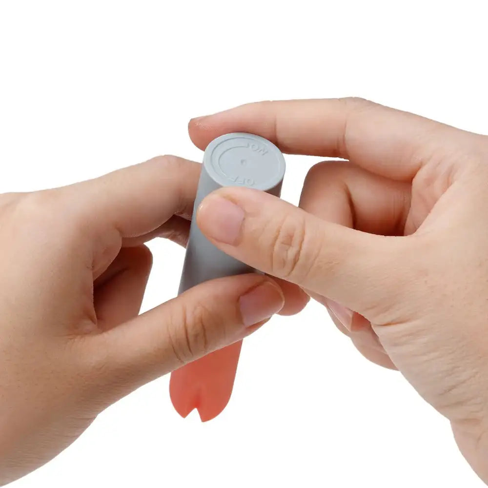 Hands inserting or adjusting battery into compact lipstick-style vibrator device