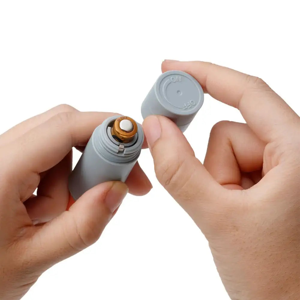 Hands opening base of vibrator to reveal battery compartment and internal parts