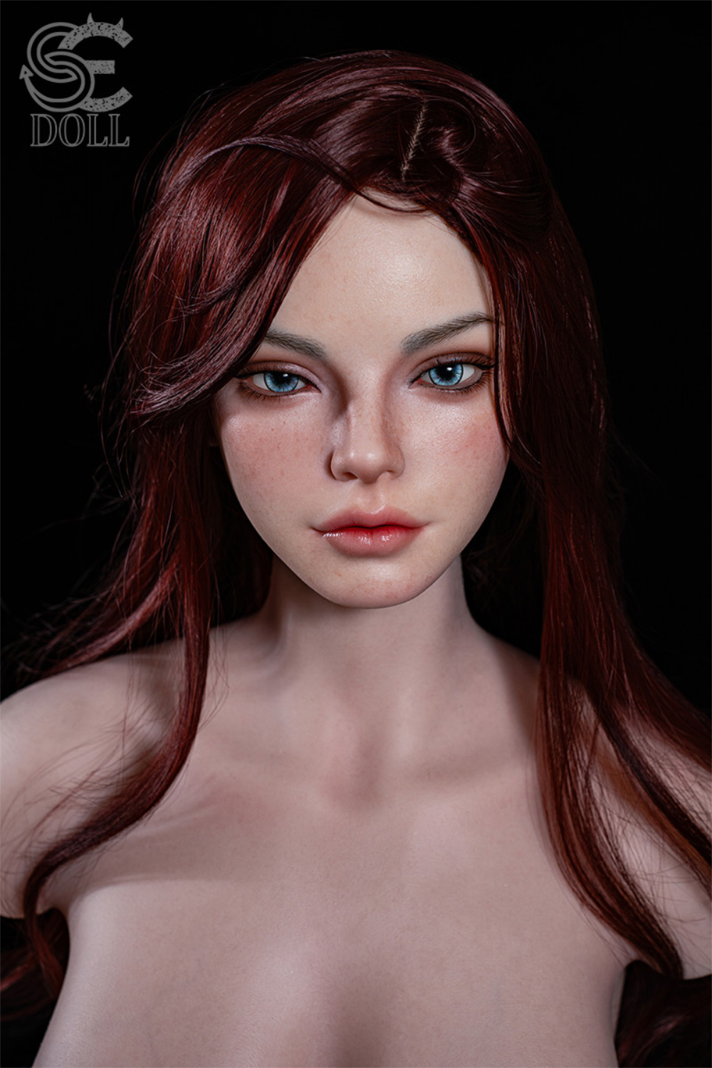 A head-and-shoulders portrait of the SEDOLL T107 cm H Silicone Torso - Scarlett Reed.A, featuring long, wavy red hair, blue eyes, and subtle freckles against a solid black background.
