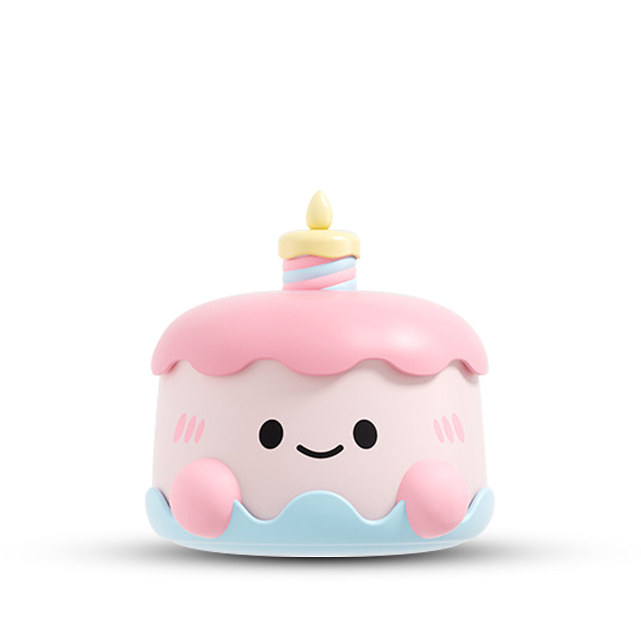 Cute pink cake-shaped massager with smiling face and candle detail on white background