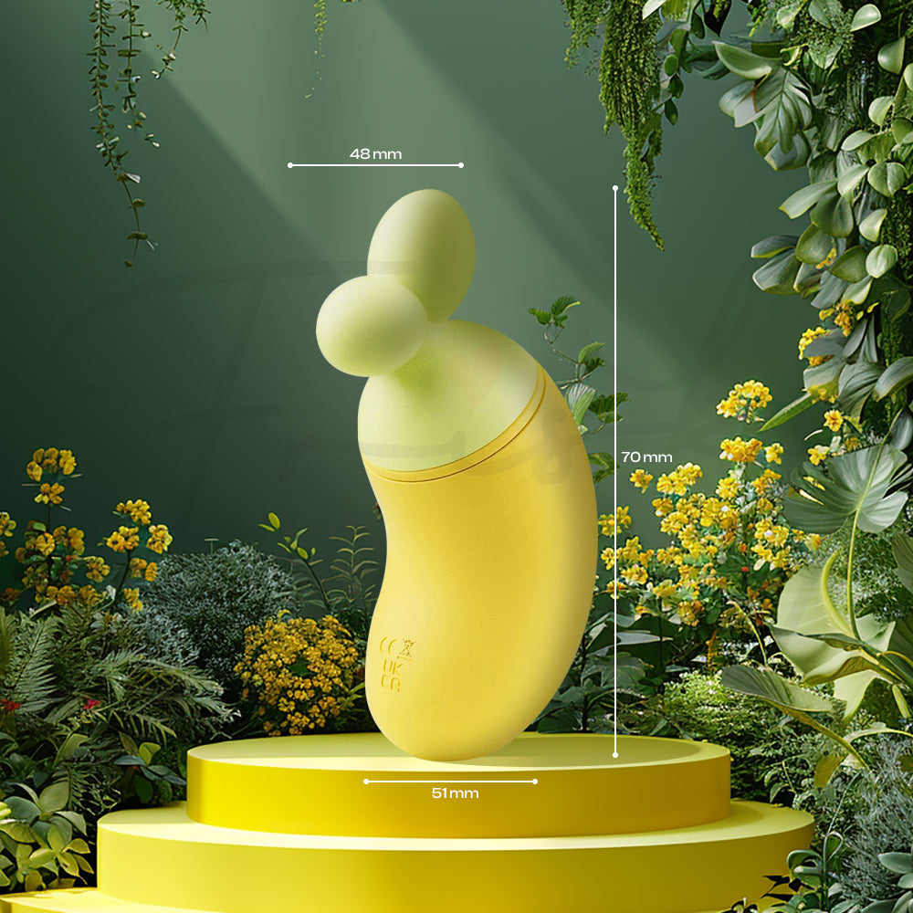 Yellow BanaRush vibrator standing on a round pedestal surrounded by lush greenery and soft natural lighting.