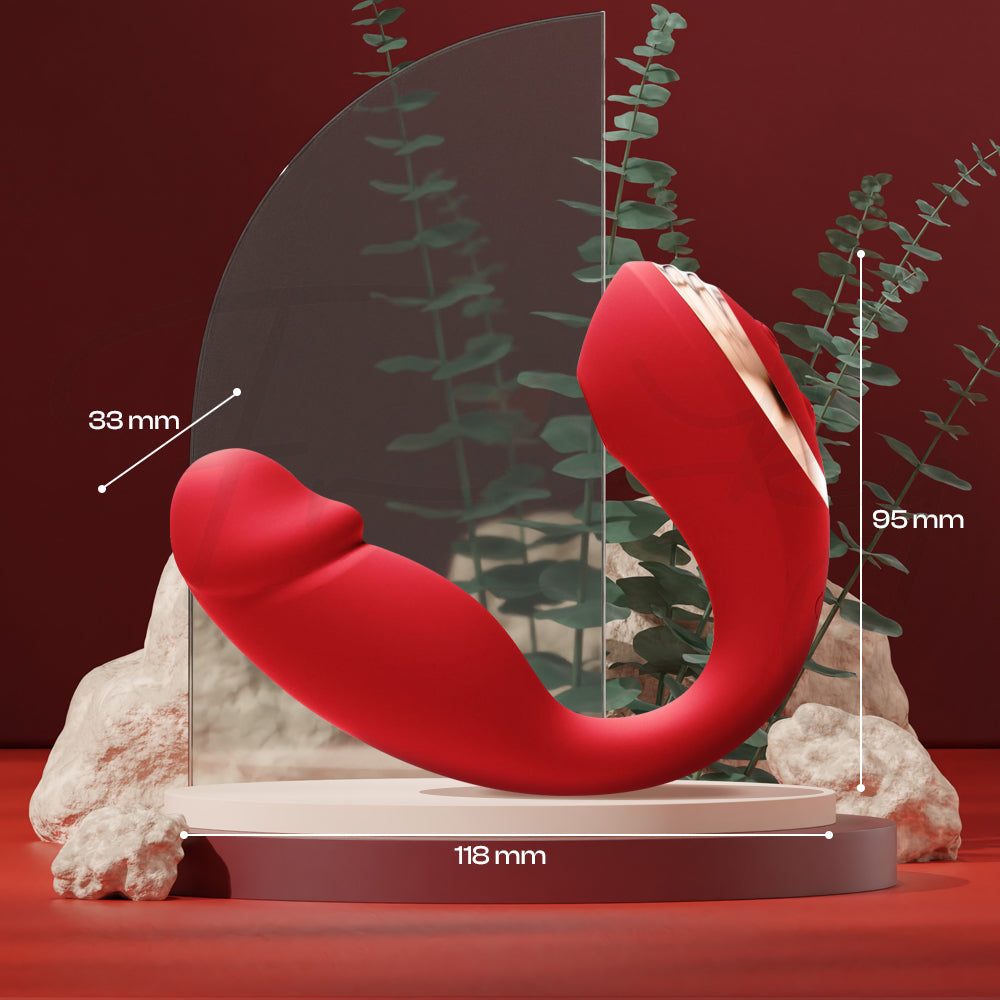 Curved red wearable vibrator resting on a stone pedestal with plants and a mirror.
