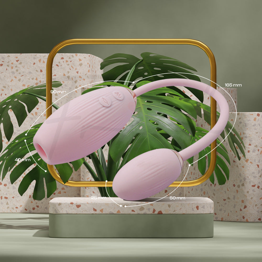 Two connected eggs in pink silicone shown resting on woven mat with greenery