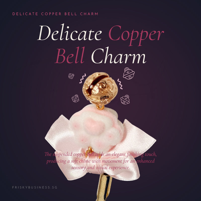 Delicate copper bell charm with pink floral element on a dark background