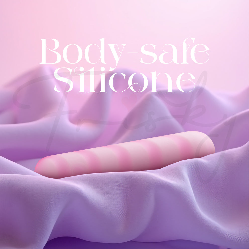 Soft pink vibrator resting on smooth pastel fabric highlighting body-safe silicone material.