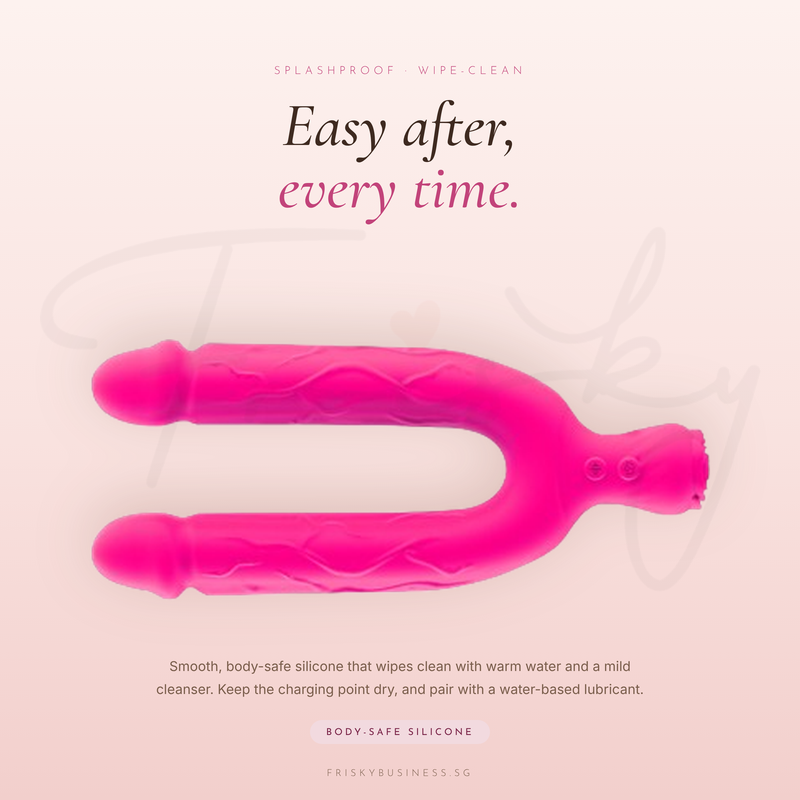 Pink U-shaped vibrator laid flat on its side against a blush background