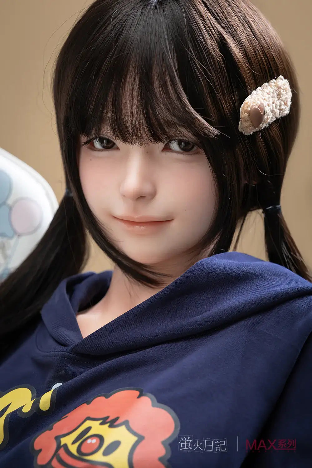 Close-up portrait of Firefly Diary Doll 165 cm Max Series Silicone – Qiandao with long dark brown hair in pigtails, soft natural makeup, and a small hair accessory, wearing a navy hoodie with a cartoon print, posed against a warm background.