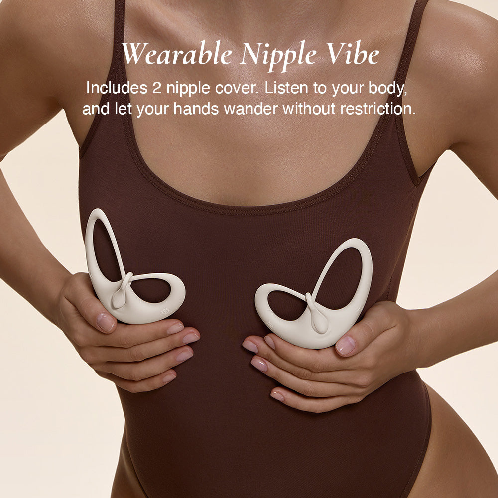 Model in brown bodysuit holding Osuga Papillon vibrator at chest level, showing its elegant butterfly-inspired design.