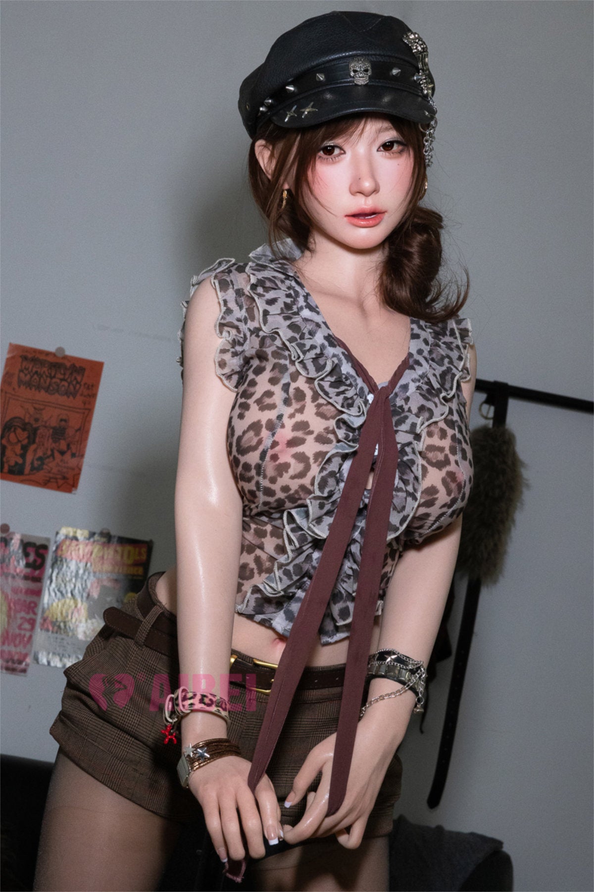 Aibei Doll 167cm E Luxe Silicone - Yuna V2 – Standing side pose, black fur-trimmed cap, animal-print bodysuit and fishnet stockings, wavy auburn hair down, eclectic graffiti wall backdrop.