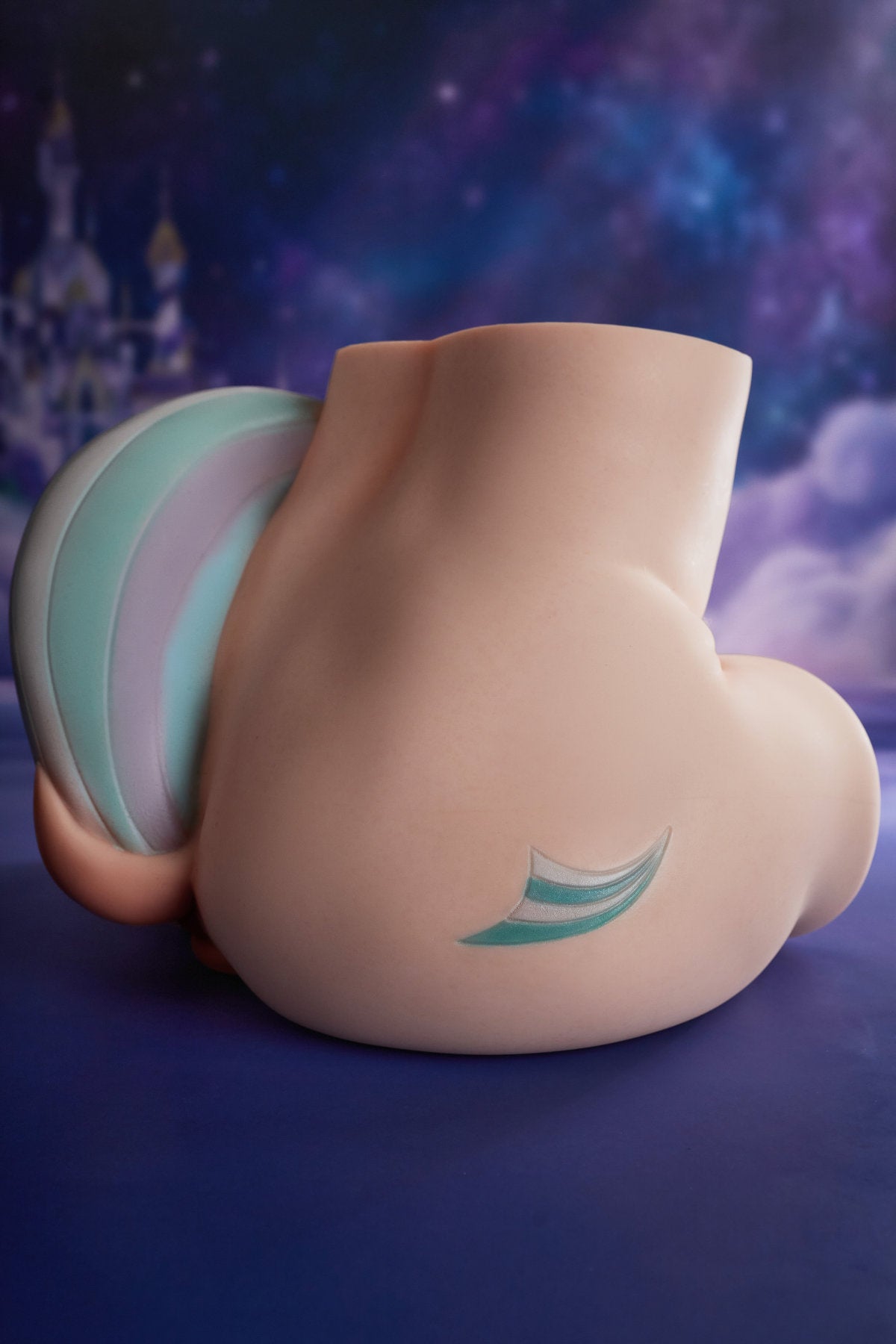 CLIMAX DOLL - PA-Razor Silicone Butt Torso (Cinnamon) full side view showing buttocks and torso with teal and pink tail accessory, galaxy blue background
