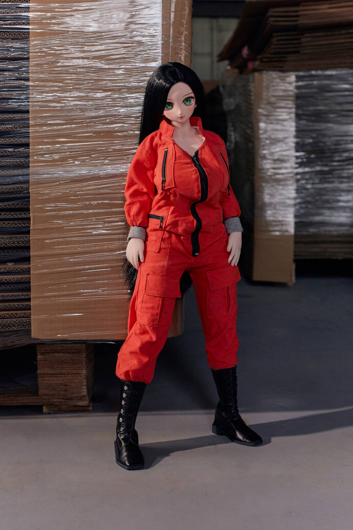 CLIMAX DOLL Mini J60cm P Hybrid - Rina (Cinnamon) full-body standing pose in the red coverall and black boots, warehouse shelving behind her