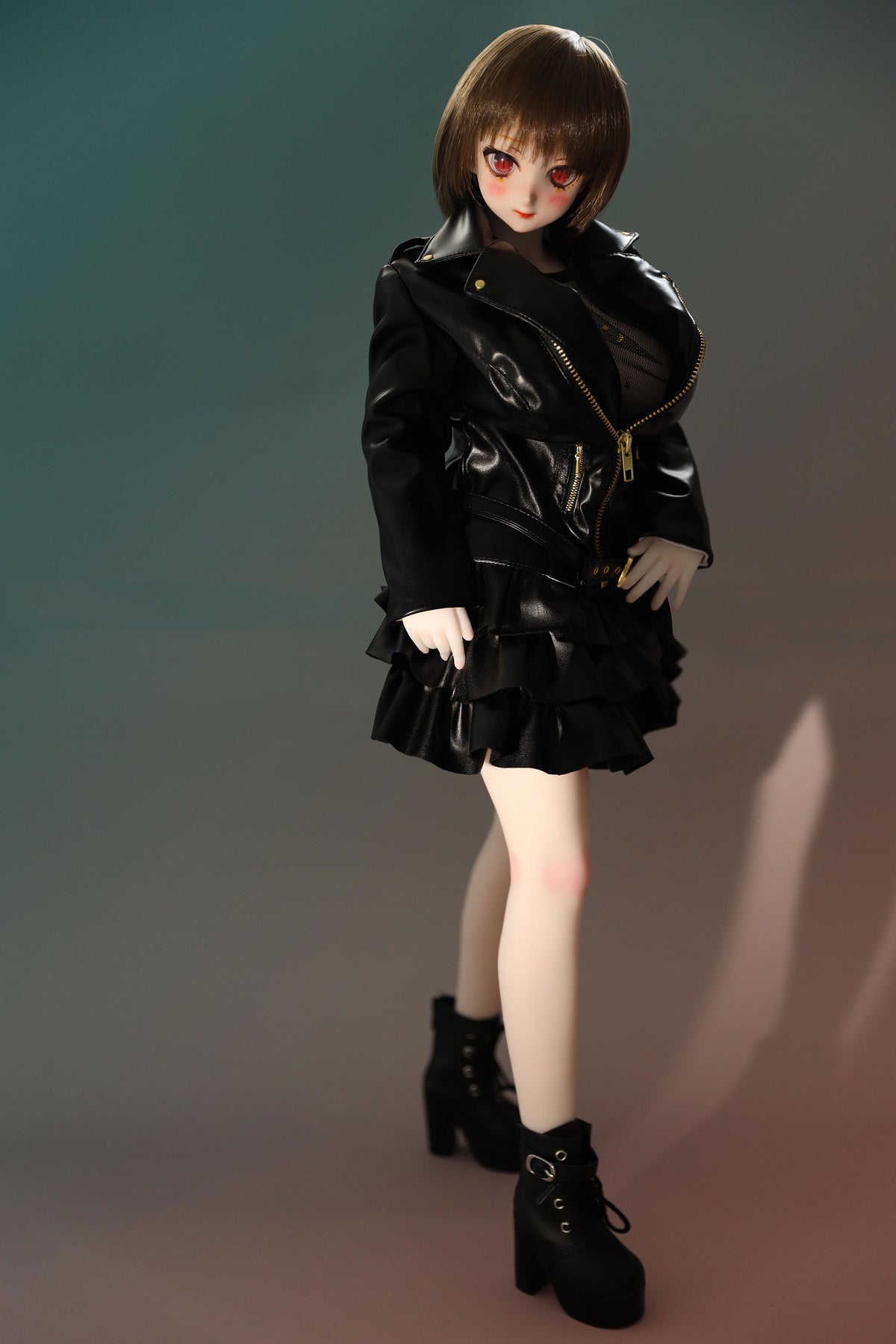 CLIMAX DOLL Mini J60cm P Hybrid - Zella (White) - Full-body standing pose in the black ruffled jacket-dress with gold zipper and black boots, arms relaxed at her sides, teal-green gradient backdrop.