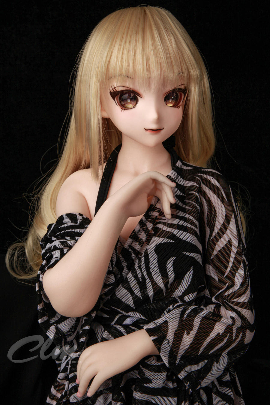 CLIMAX DOLL Mini J60cm XS Hybrid - Nagisa (Cinnamon) close-up portrait, long wavy honey-blonde hair, large brown anime eyes, sheer zebra-print robe slipping off one shoulder, hand resting near her collarbone, black studio backdrop