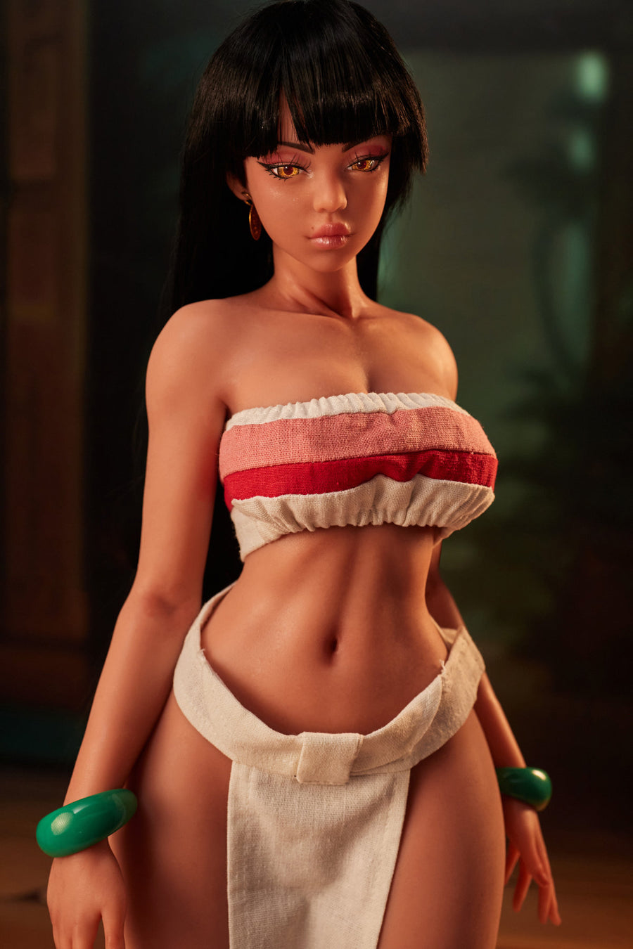 CLIMAX DOLL Mini Si70cm MO Silicone - Roxy (Black) full body standing pose in red and white tribal bikini top and wrap skirt with green wrist accessories, short dark hair, warm temple indoor background
