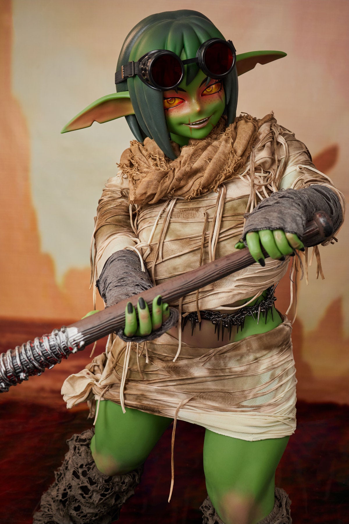 CLIMAX DOLL ULW SiF120 cm Silicone - Barza (Green) full body front view in tattered tan wrap with staff accessory, short green hair, desert red background

