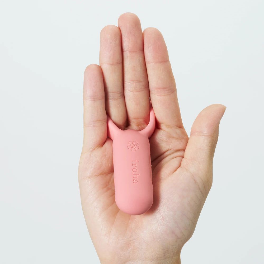 Pink silicone tool held in a hand against a light gray background