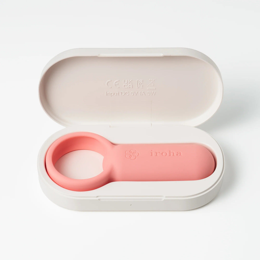 Pink ring vibrator placed inside open charging case with minimal aesthetic