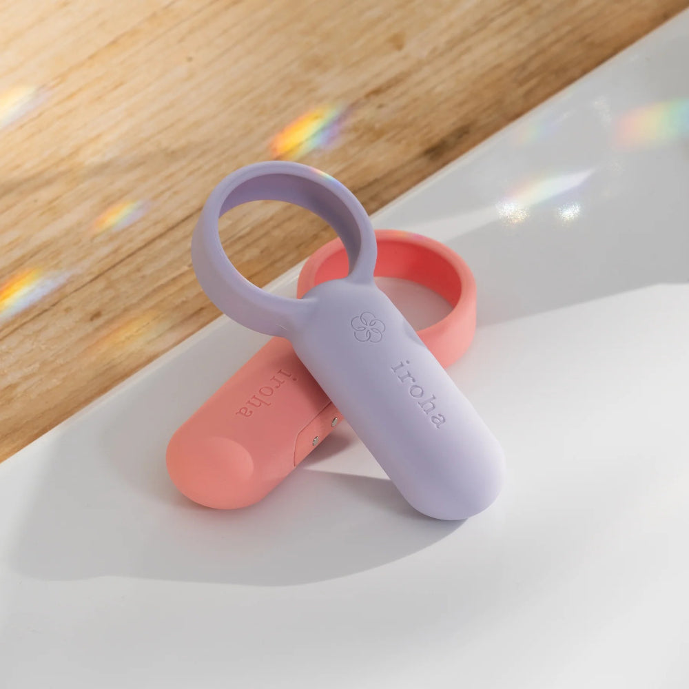 Pink and purple wearable vibrators placed on wooden surface in natural light