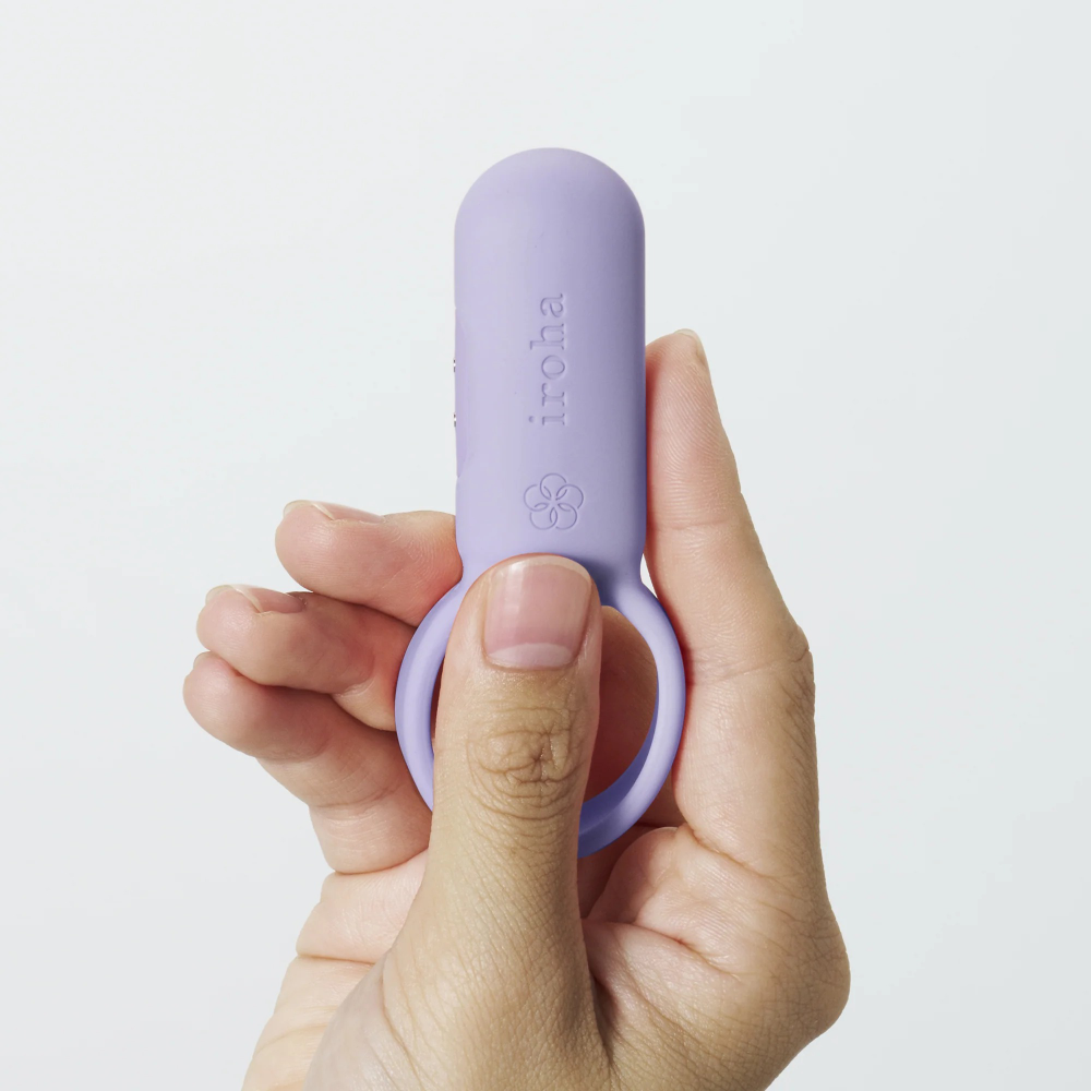 Hand holding small purple vibrating ring showing compact size and smooth silicone texture