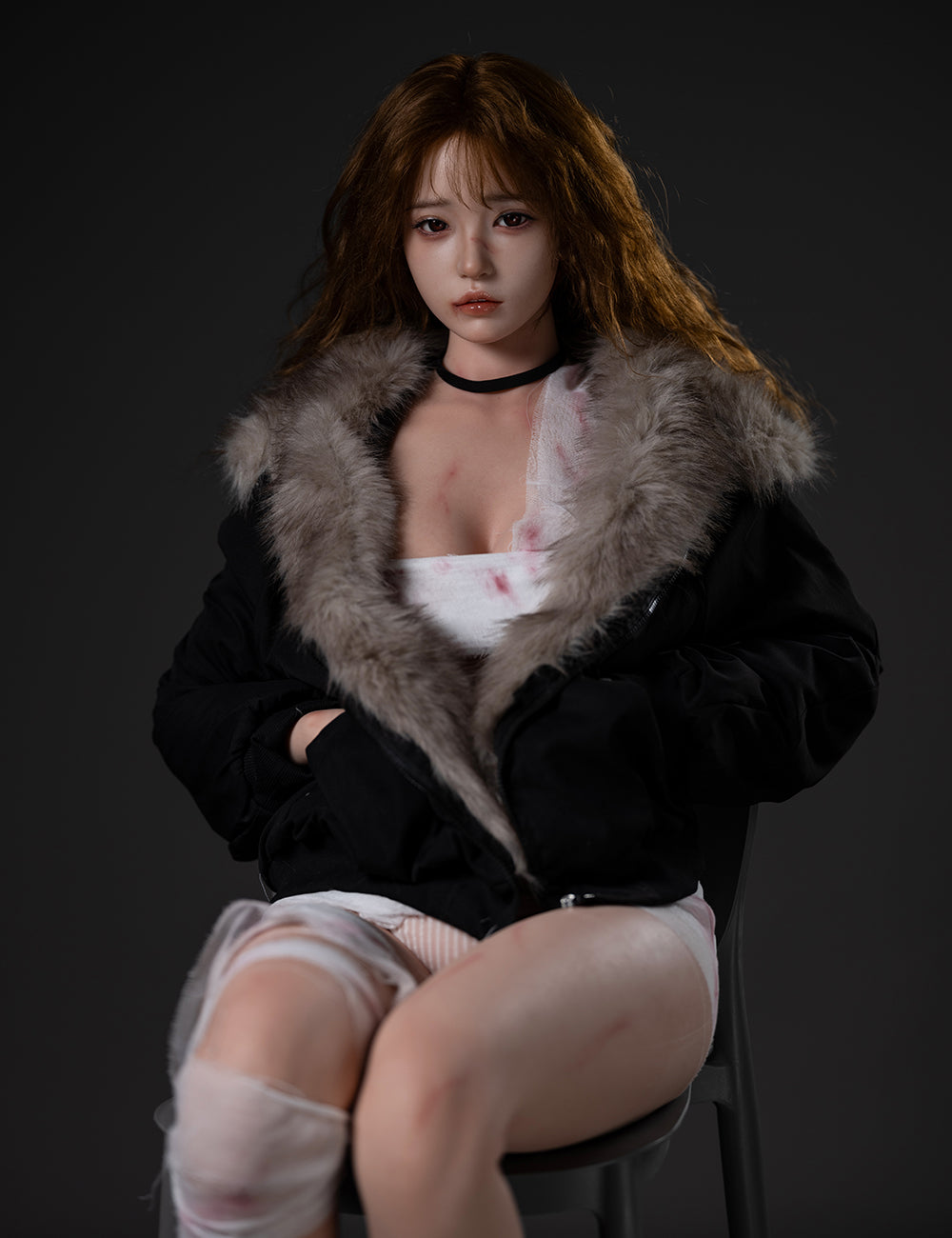 TOP-CYDOLL 162cm E-Cup Liang Realistic Sex Doll seated and wearing a black winter parka with a fur-lined hood over blood-stained bandages and faint body bruises.