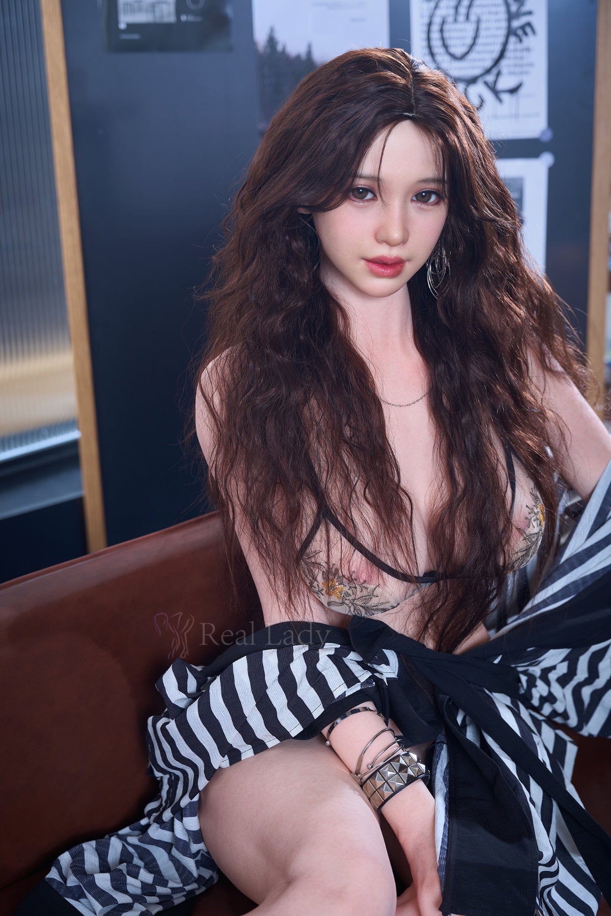 RealLady 159cm H Silicone - Alodia V4 – Seated pose in striped cardigan, dark lace lingerie, long wavy brown hair framing the face, warm indoor backdrop.
