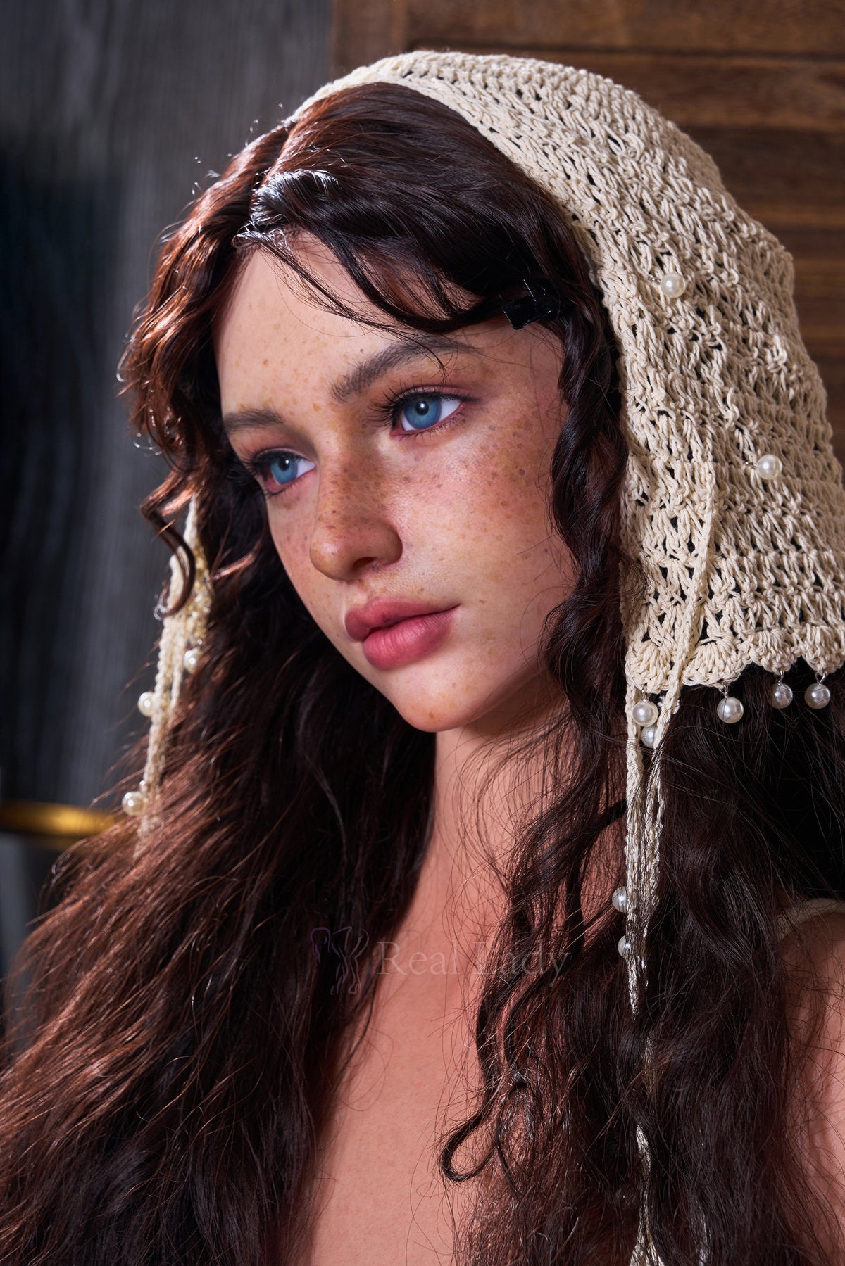 RealLady 159 CM H Silicone - Lena V4 close-up portrait view wearing white crochet headscarf, showcasing realistic facial features with long dark wavy hair and natural freckle details against warm rustic indoor background

