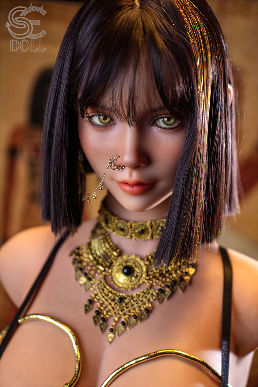 SEDOLL T111 cm G Silicone Torso - Kemeny.C close-up upper body shot in gold Egyptian-style collar necklace with black strappy harness, short dark hair with gold braided accessories, warm temple background
