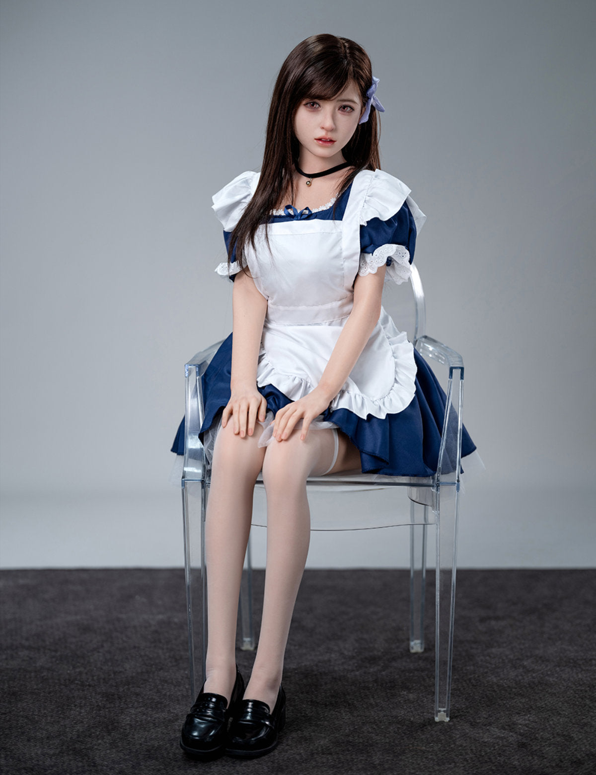Full-length front shot of the 157cm Koharu doll seated on a clear chair, showcasing the full maid uniform and black shoes.