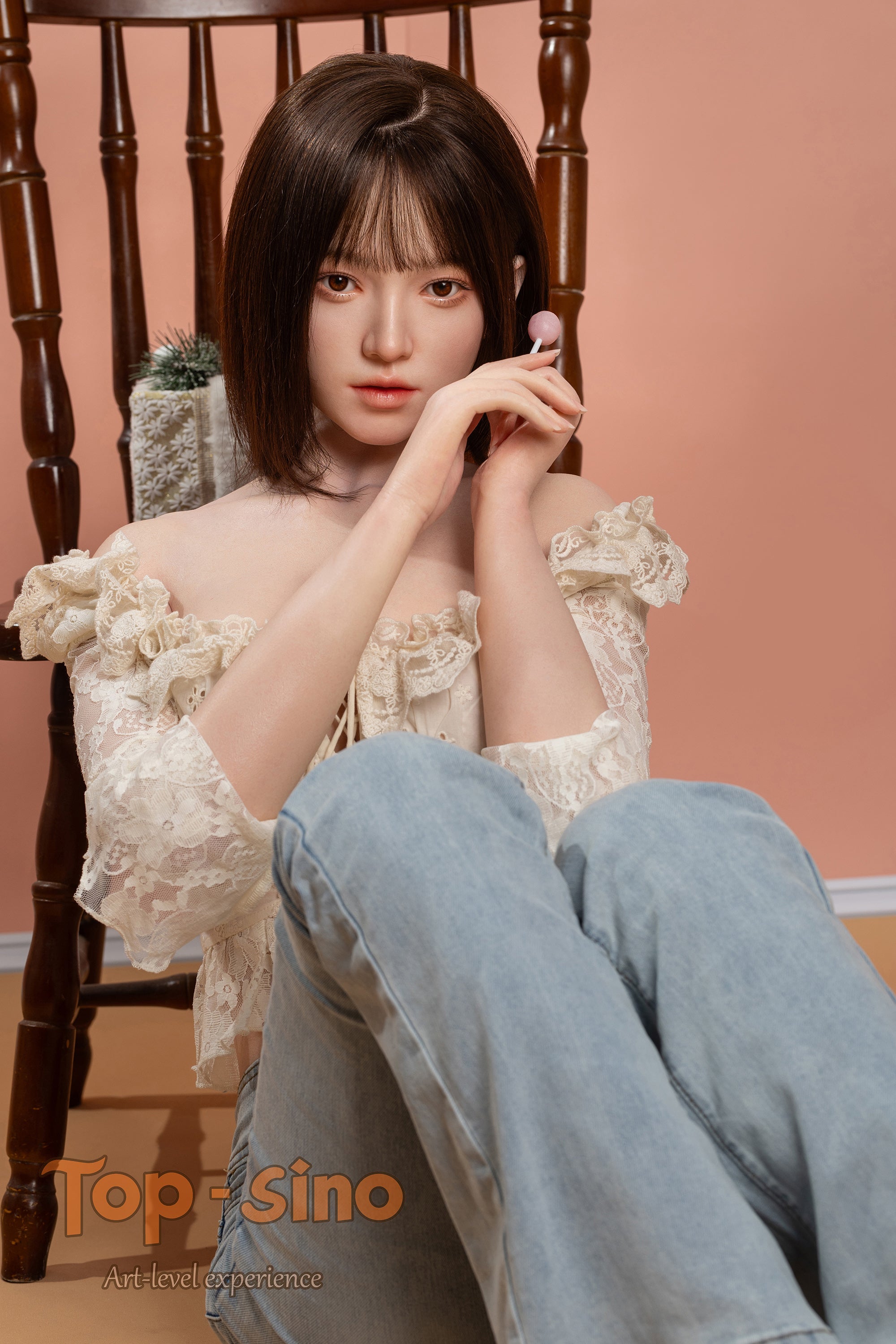 Top Sino 167 cm Platinum Silicone - Mimu (RRS+) - V2 sitting in front of a wooden chair wearing a light-colored top with floral details and light blue jeans.