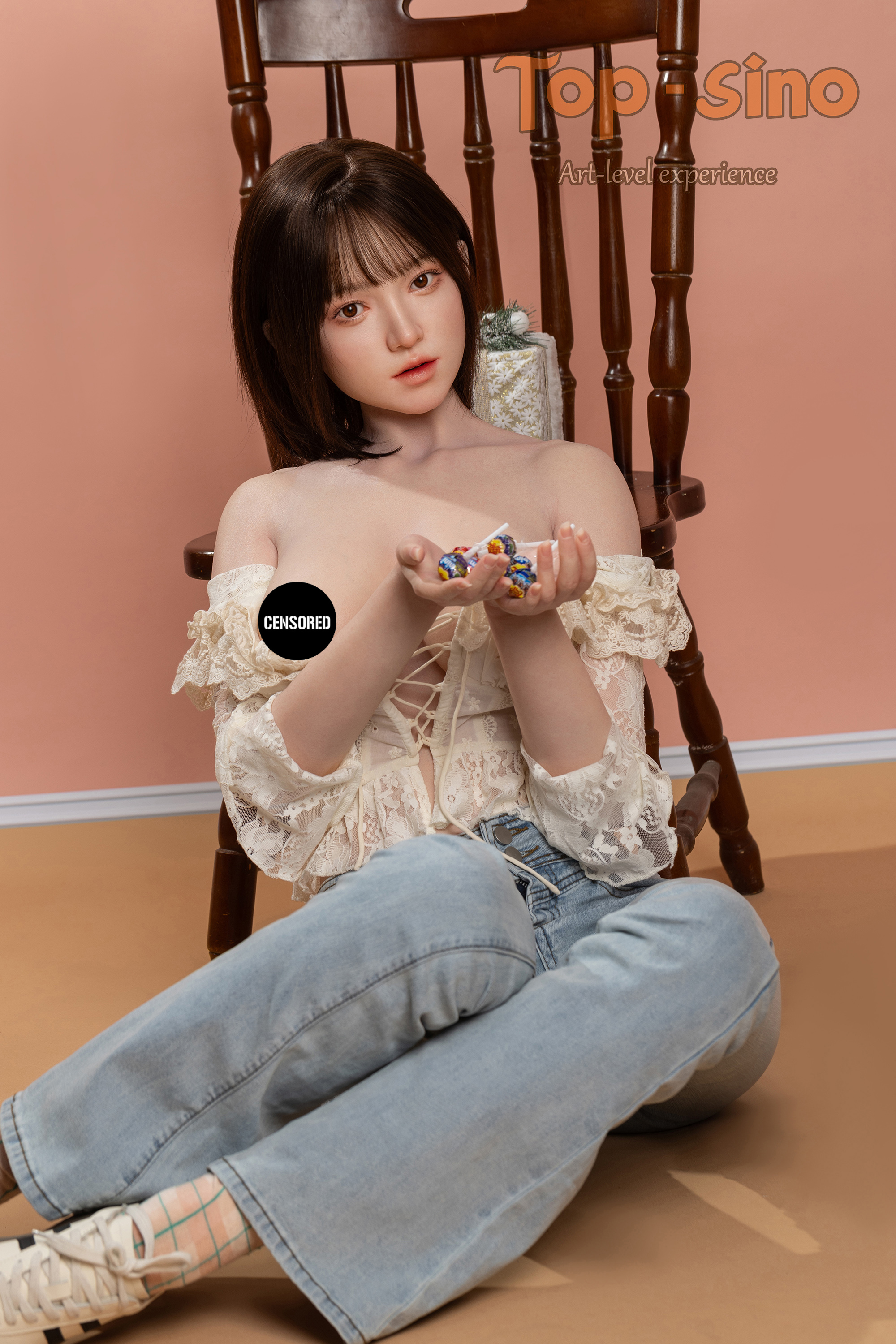 Top Sino 167 cm Platinum Silicone - Mimu (RRS+) - V2 wearing a beige top while holding colorful lollipops against a peach wall.
