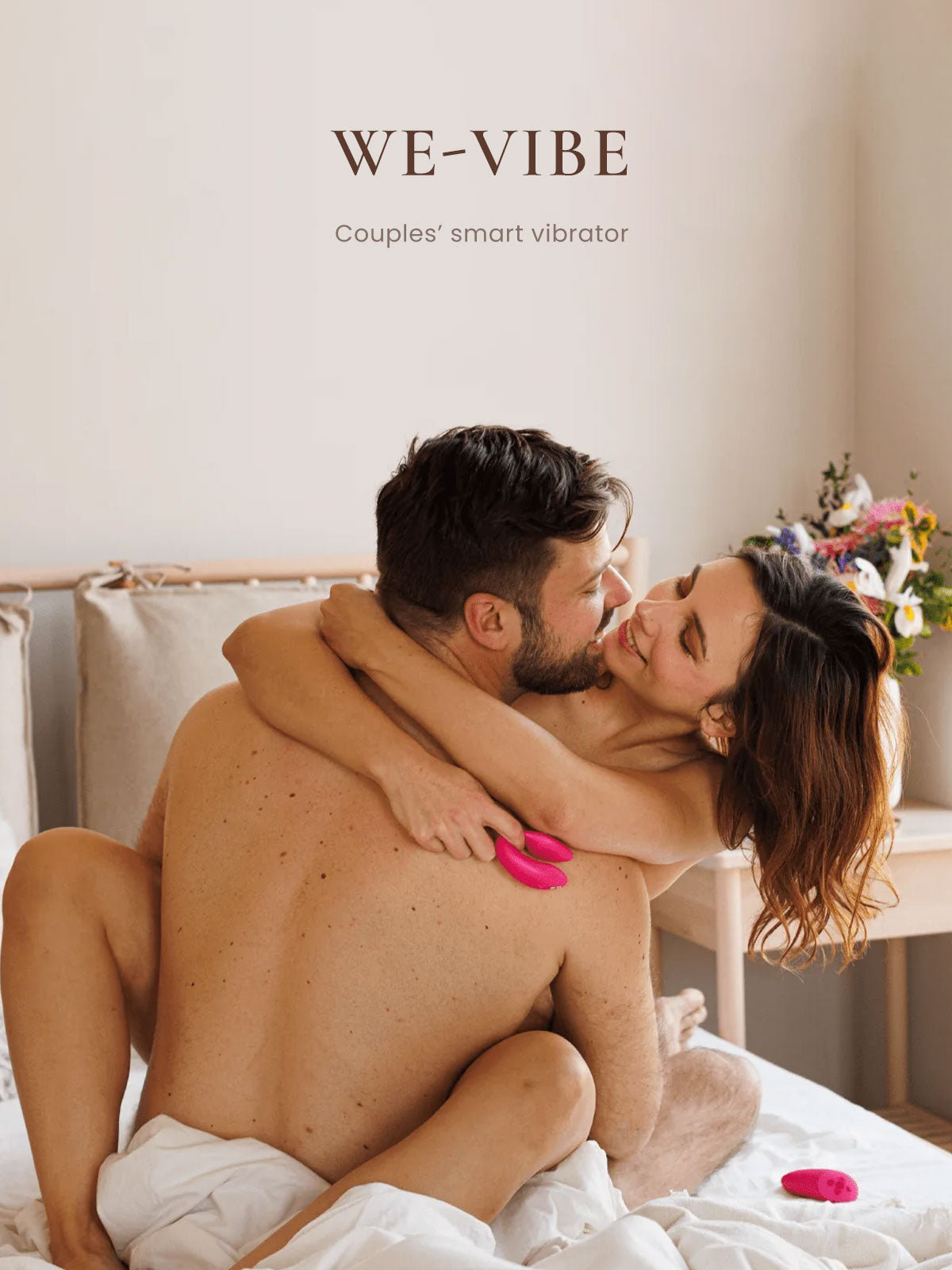 Couple using a 'WE-VIBE' couples' smart vibrator in a bedroom setting.