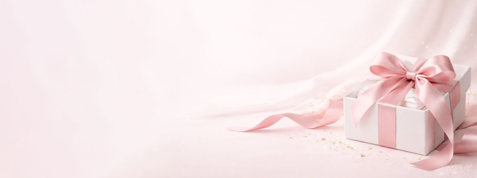 White gift box with a pink ribbon on a light pink background