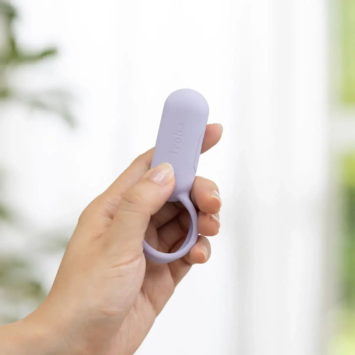 Hand holding a purple tool against a blurred natural background
