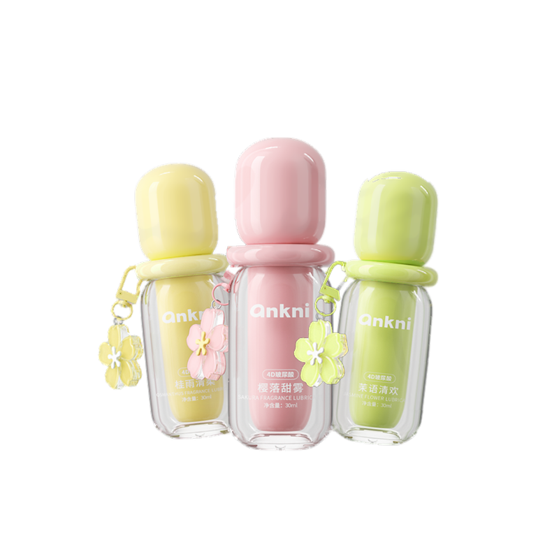 Three small lubricant bottles in yellow, pink and green with flower charms on white